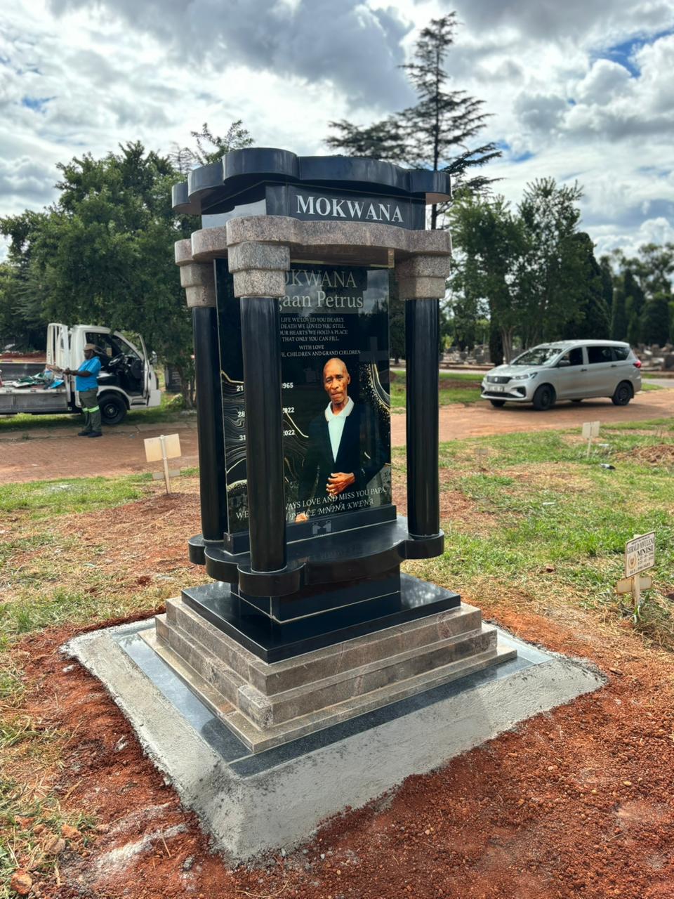 A complete tall polished granite memorial with a portrait and stepped base